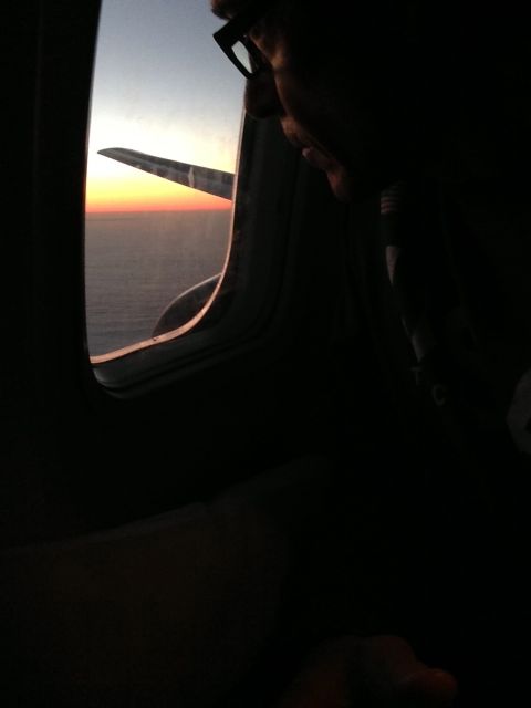 baby Boomer looking out airplane window at dusk