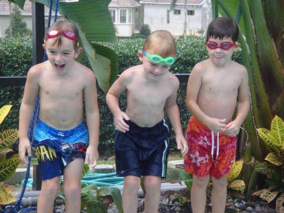 Three five year old boys having fun poolside