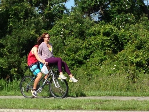 young man riding bicycle with young woman sitting on handle bars