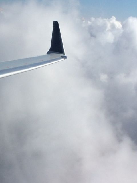 Jet wing against white fluffy clouds
