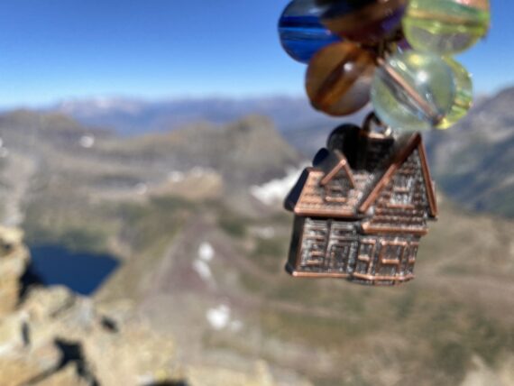 mountains and a pendent made of a small house and balloons.