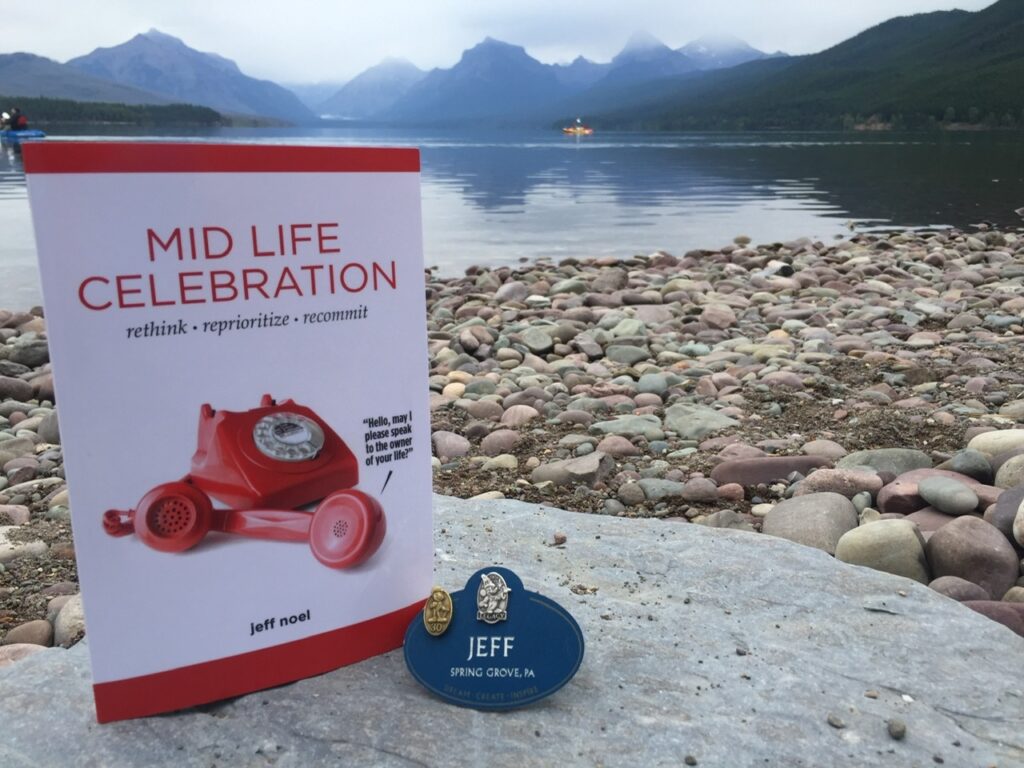 Mid Life Celebration, the book, and Disney Legacy name tag at mountain lake