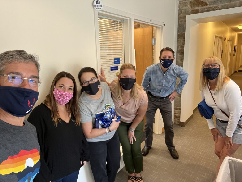 Six people wearing masks in a hallway
