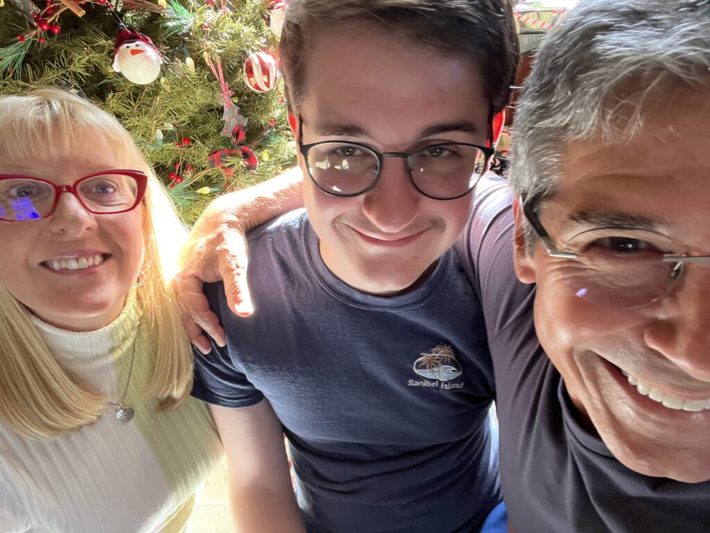 Family of three next to Christmas tree