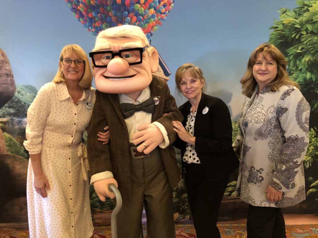 Disney Pixar character Carl posing with three women
