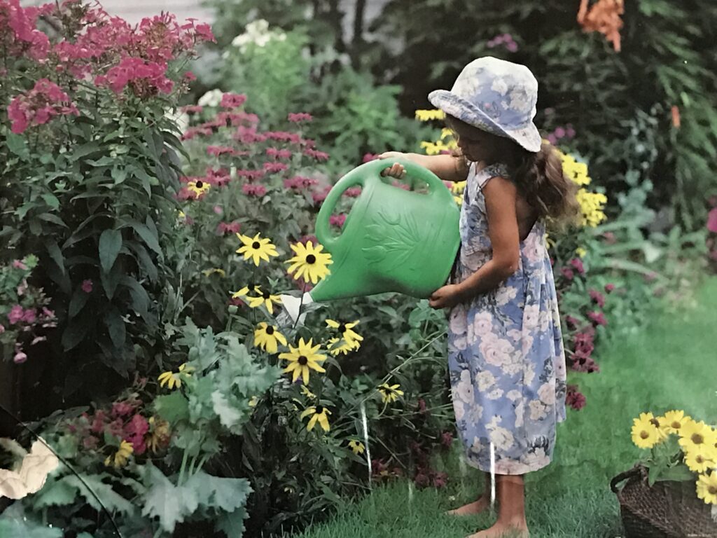 child watering flower garden