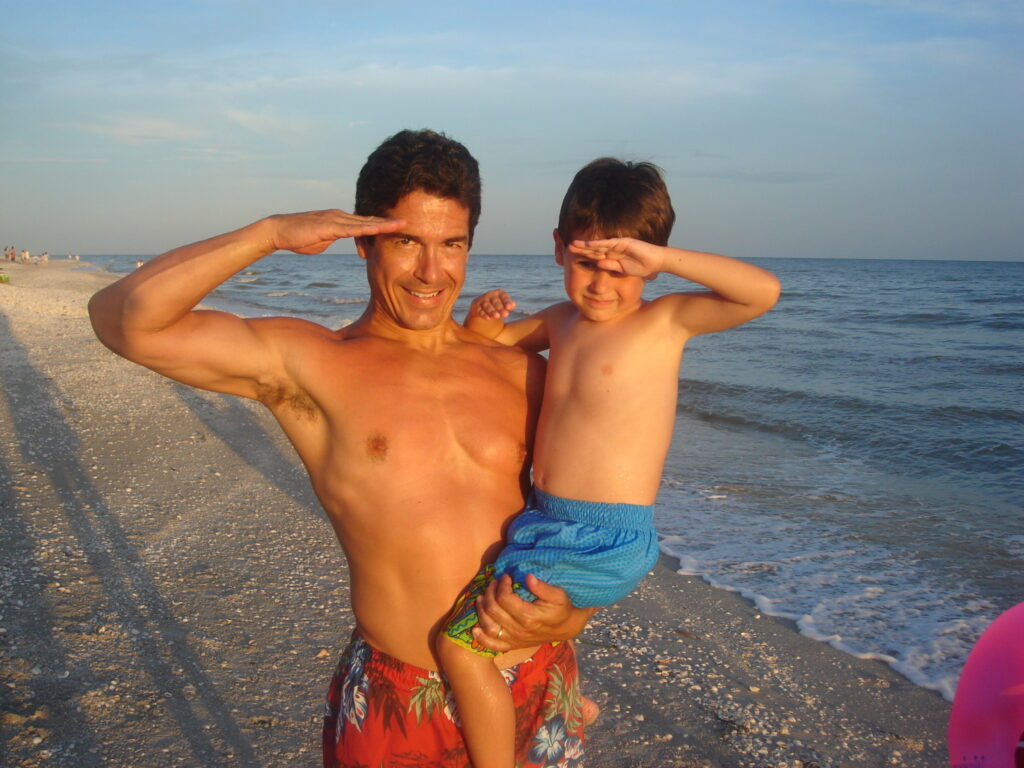Father and son saluting at beach
