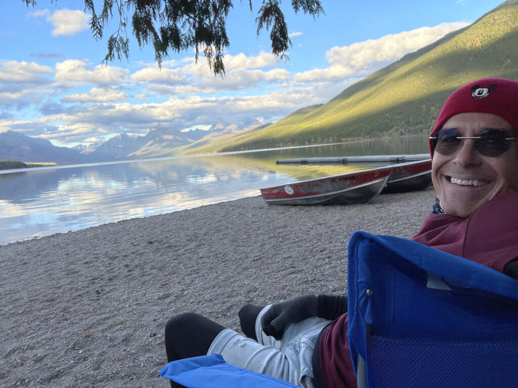 man sitting by mountain lake