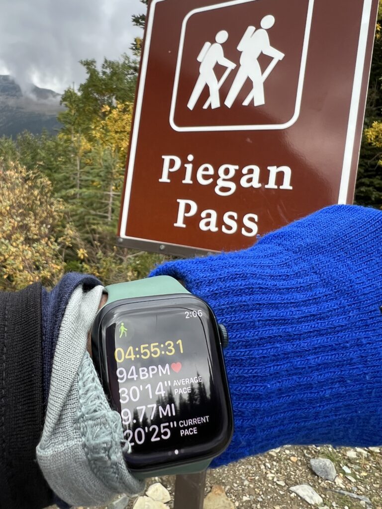 Apple Watch in front of trail head sign